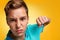 Emotions and transitional age. Close-up portrait of a teenage boy in a blue t-shirt, with an angry face and a fist. Yellow