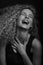 Emotive black and white studio portrait of cute young woman with curly hair.