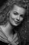 Emotive black and white studio portrait of cute young woman with curly hair.