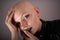 Emotive portrait of a bald woman while covering her face