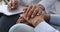 Empathic young nurse holding hand supporting elderly patient.