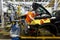 An employee of an automobile plant assembles an engine under the hood of a new car