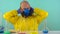 An employee of a chemical laboratory in a protective yellow suit, gloves and mask, finished the experiment, takes off