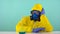 An employee of a chemical laboratory in a protective yellow suit, gloves and a mask, in front of him a flask with