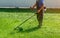 Employee mows green grass on the lawn with portable lawn mower