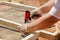 An employee is nailing a metal mesh to a frame made of wood with a nail gun