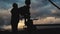 An employee in overalls and a helmet is carrying out repairs and maintenance of an oil well. Silhouette on the