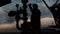 An employee in overalls and a helmet is carrying out repairs and maintenance of an oil well. Silhouette on the