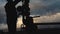 An employee in overalls and a helmet is carrying out repairs and maintenance of an oil well. Silhouette on the