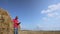 employee stands near bale of straw and makes recordings in tablet