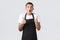 Employees, grocery stores and coffee shop concept. Impressed and speechless handsome waiter in black apron, drop jaw and