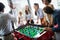 Employees playing table soccer indoor game in the office during break time