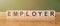 EMPLOYER. Word written on wooden blocks on wooden table. Concept for your design