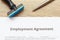 Employment Agreement document lay down on wooden desk with rubber stamp and pen