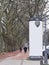 Empty advertising pillar in a city with free copy space, promotion mock up. Blank advertising panel.Unidentifiable pedestrians