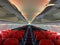 Empty aircraft cabin with male cabin crew working in galley. premium and economy seat row in cabin. red seat and black seat.