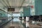 Empty airport lounge area with seats, moving walkway, trash cans and scoreboard.