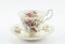 Empty antique cup and saucer with rose decoration isolated