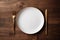 empty artistic ceramic Glazed earthenware white fancy shape plate, golden cutlery on side.