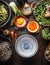 Empty asian bowl with chopsticks and ingredients for noodles meal with green vegetables and soba on dark rustic background with