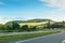 The empty asphalt road and blue sky with white clouds on the sunny day. Classic panorama view of road through fields