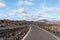 Empty asphalt road road through arid volcanic landscape against sky