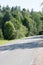 Empty asphalt street/road in Hot Summer weather. Forest with different trees in the background. Road turn. Natural color.