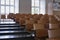 Empty auditorium at university with wooden chairs and banks and large windows and stairs on one side.