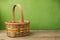 Empty basket on wooden table over grunge green background