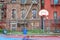 Empty basketball court on a rainy day. Surrounded by a fence and between homes. Harlem, NYC, USA