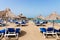 Empty beach with chairs, sunbeds, straw umbrellas, and blue sky. Mediterranean summer vacation destination, Heraklion