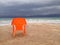 Empty beach with a lonely orange chair under a dramatic deep blue sky, the Dead Sea, Israel.