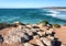 Empty beach and stone seasside in Portugal. Ocean waves at sunny day of Algarve area