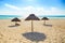 Empty beach with three thatched sun umbrellas