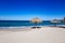 Empty beach with two palapas on sand, sea and the horizon in background against clear blue sky