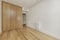 Empty bedroom with custom built built-in wardrobe with light oak wooden doors, ducted air conditioning on the ceiling, white