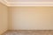 Empty beige interior with blank wall, mouldings, ceiling backlit and wooden chevron parquet floor.