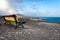 An empty bench, painted in a rainbow of colors and a view of Playa de Sotavento de Jandia.