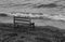 An empty bench seat on beach across waves