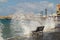 An empty bench stands on the edge of the embankment of Chania about which waves and a lot of splashes beat