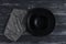 Empty black plate, fork and knife on napkin, rustic dark background. View from above, horizonal projection.