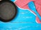 empty black round nonstick frying pan with handle on blue wooden background