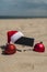 Empty blackboard frame board with copy space for your text or design displays on sandy beach. Christmas balls Santa hat