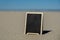 Empty blackboard frame board with copy space for your text or design displays on sandy beach. Summer vacation and