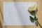 Empty blank paper letter note and white rose on wood table with window light