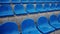 Empty bleacher in sports stadium in rainy weather. Colored wet seats in street stadium. It's raining. Close up.