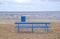 Empty blue bench and rubbish box on sea beach