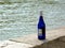 Empty blue color wine bottle on the river bank of the Danube