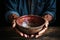 Empty bowl held by aged hands on wood, signifying the struggles of poverty