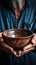 Empty bowl held by aged hands on wood, signifying the struggles of poverty